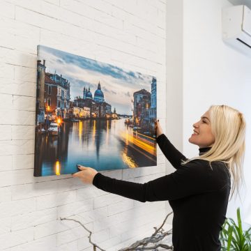 Attractive happy young woman wearing holding photo canvas in her hands